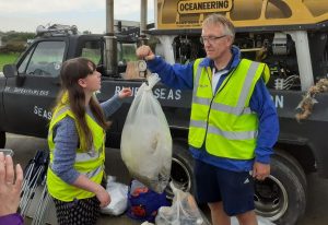 Intertek bleach clean event, people with large bag of plastic rubbish