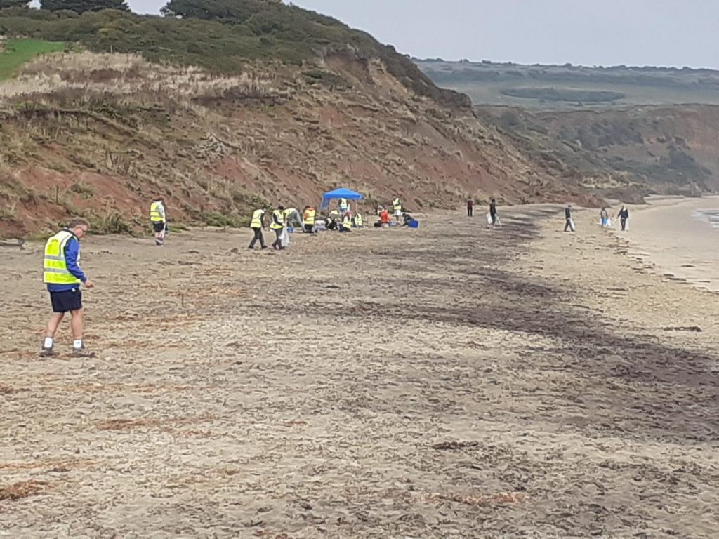 people in high vis jackets at beach cleaning event on the Isle of Wight